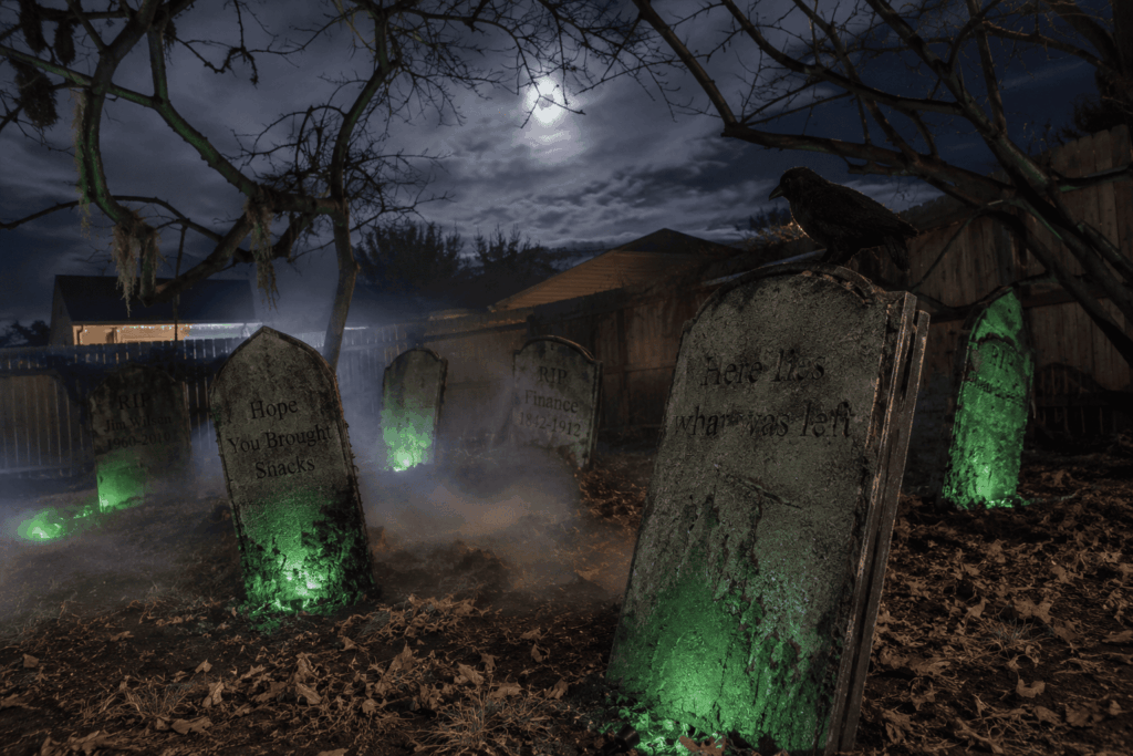 Décor de cimetière Halloween réaliste dans un jardin de nuit, avec pierres tombales vieillies, corbeau noir, branches tordues, feuilles mortes, brume épaisse et éclairages verts projetant une ambiance effrayante sous la lune.